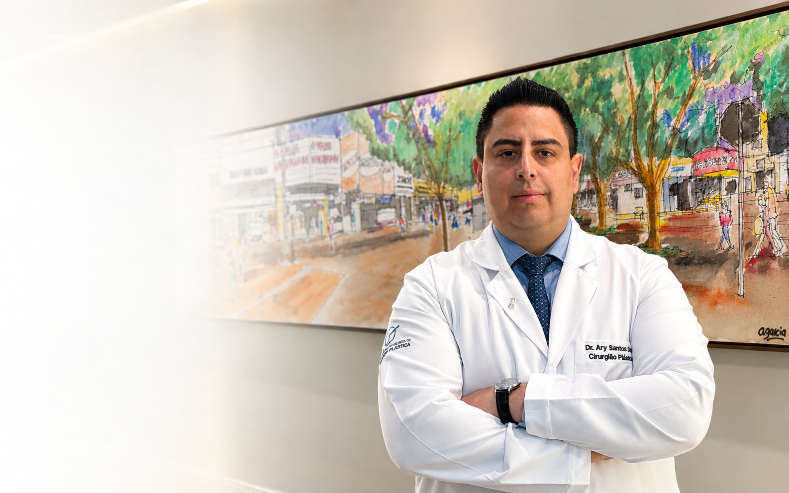 Dr. Ary Santos Silva, de jaleco e braços cruzados, diante de uma pintura de uma rua arborizada de Cascavel